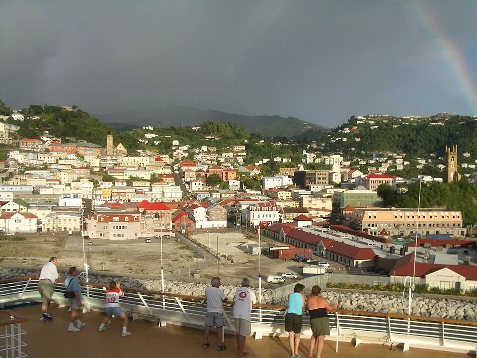 Colourful hillside buildings in St. George's, Grenada, beneath a rainbow