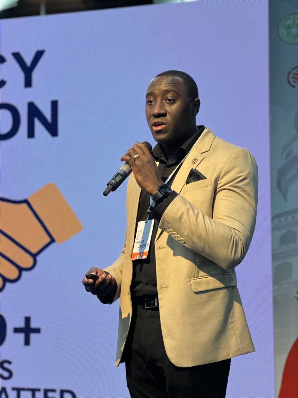 Emeka Farrier speaking at a WSA event, holding a microphone.